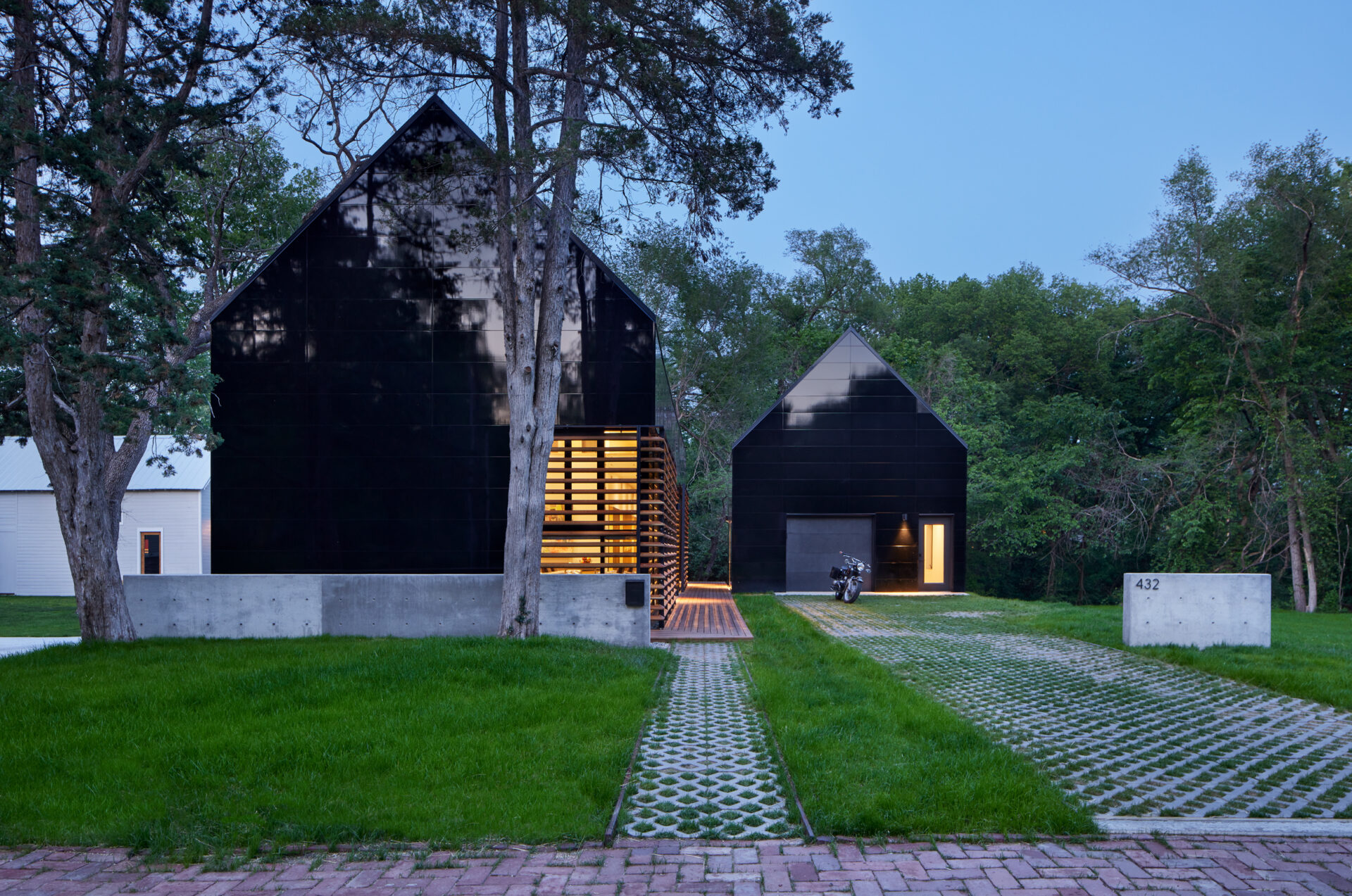 Modern house with detached garage, both with gable roofs and the same reflective black cladding. 