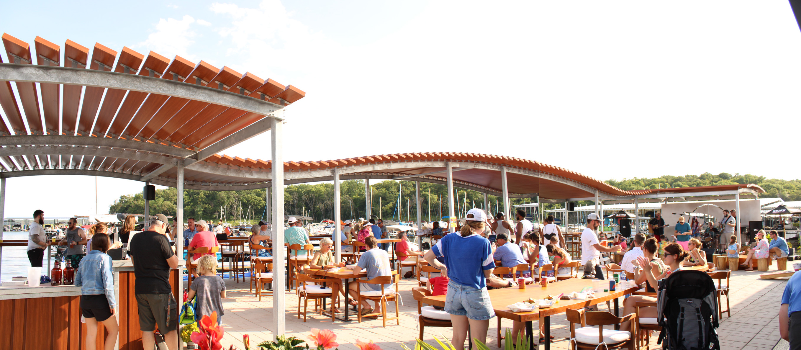 An image of tables and chairs on a floating dock, with a curved shading device overhead