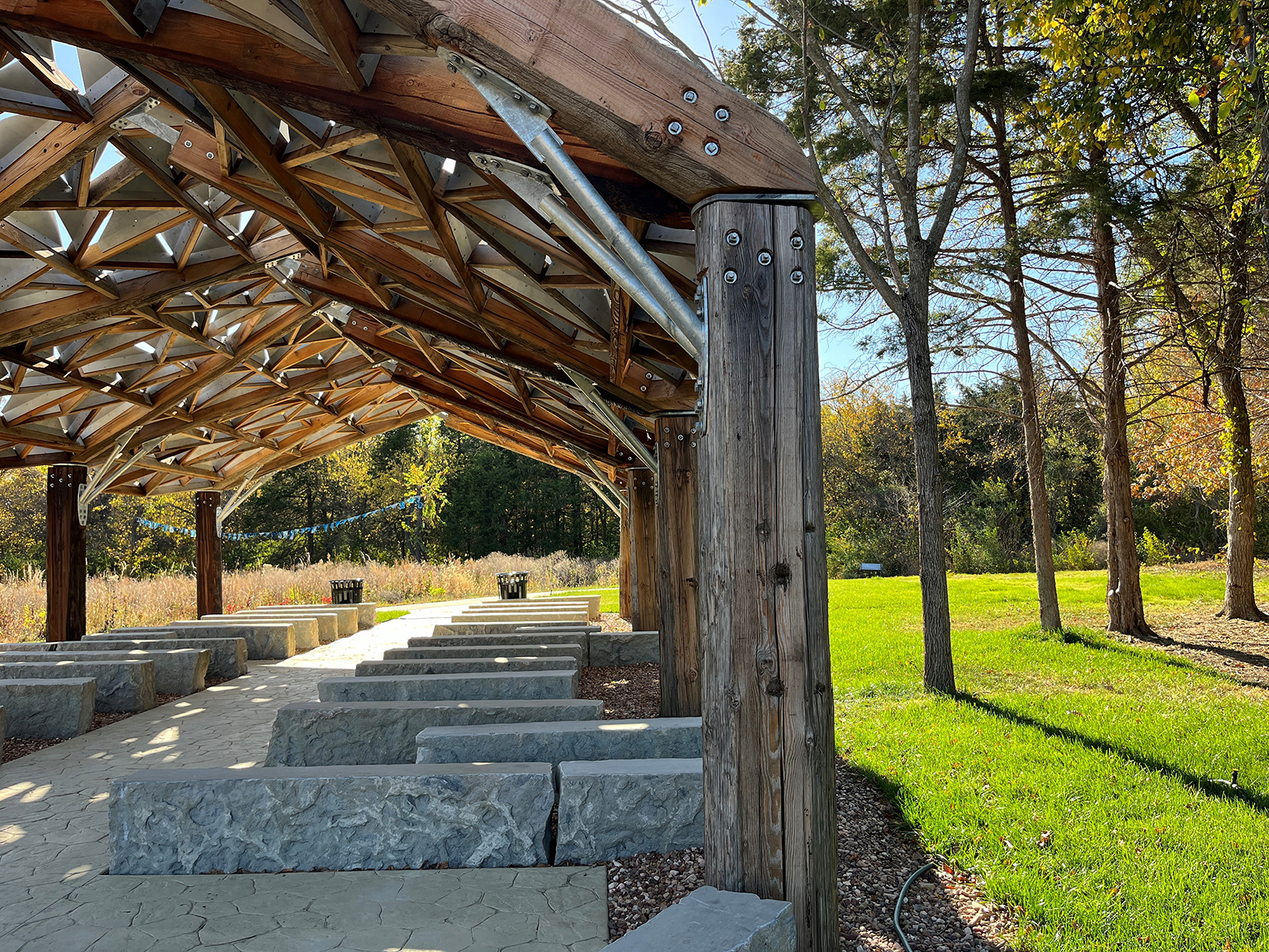 Architectural pavilion with stone seating and trees nearby